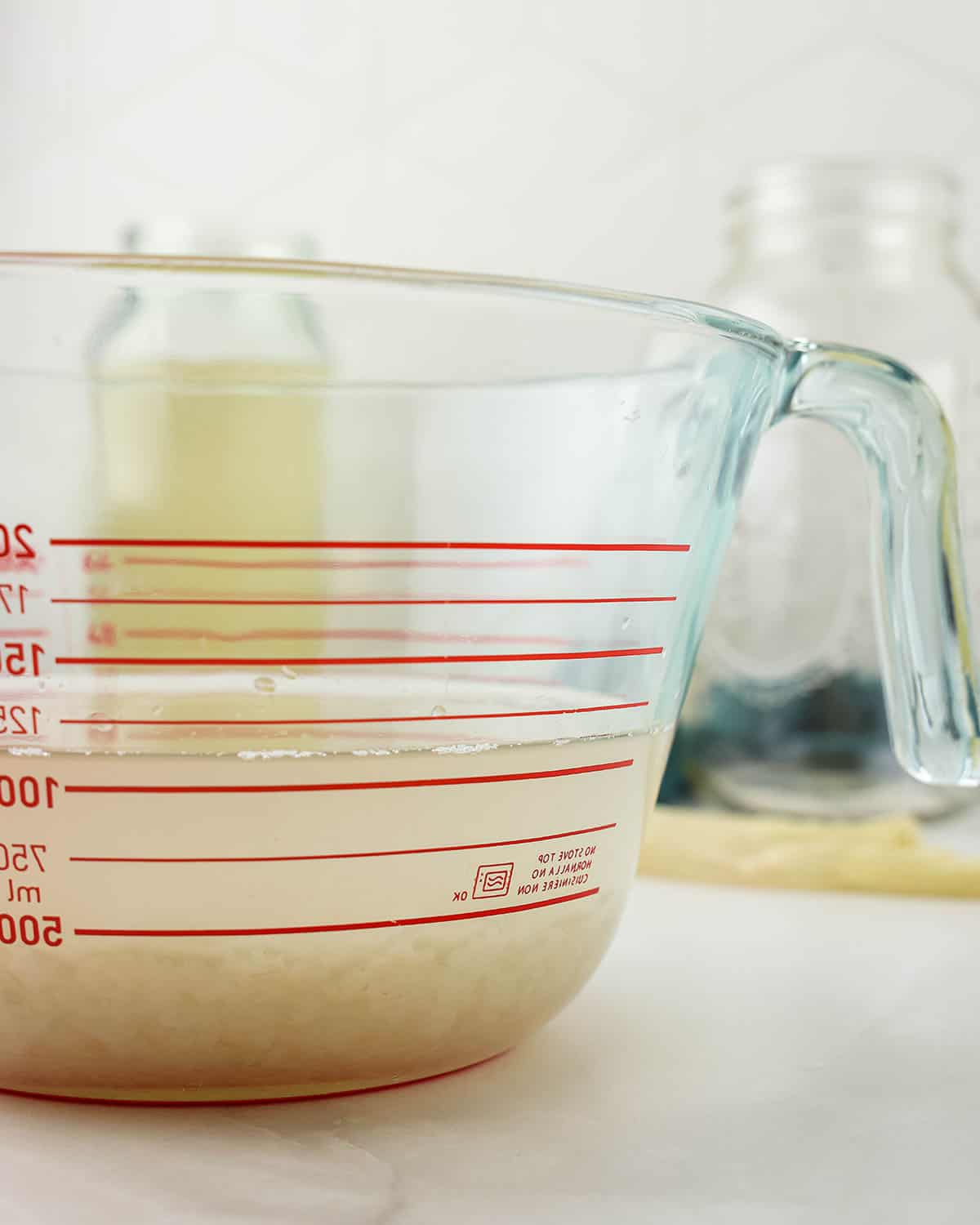 Water kefir grains in a clear bowl with liquid, side view. 