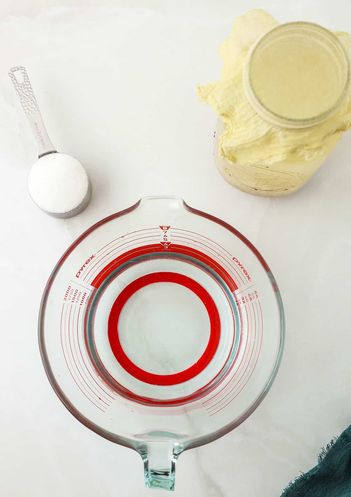 Ingredients to make water kefir in a measuring bowl, spoon, and a jar. Top view. 