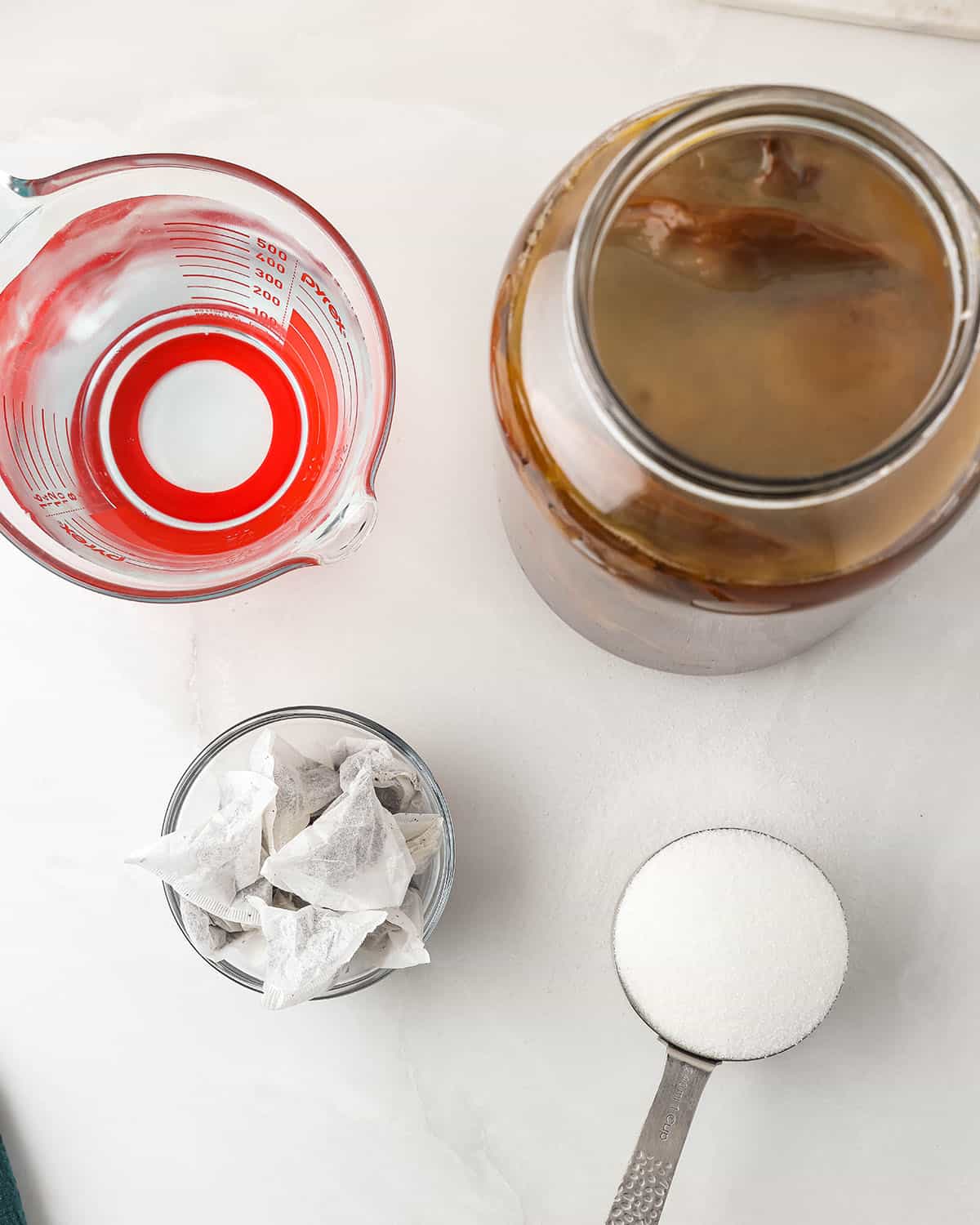 Kombucha ingredients, in measuring cups and a jar, top view. 