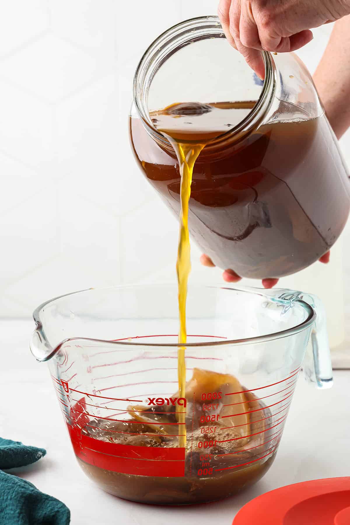 Kombucha starter pouring into a glass bowl with a SCOBY. 