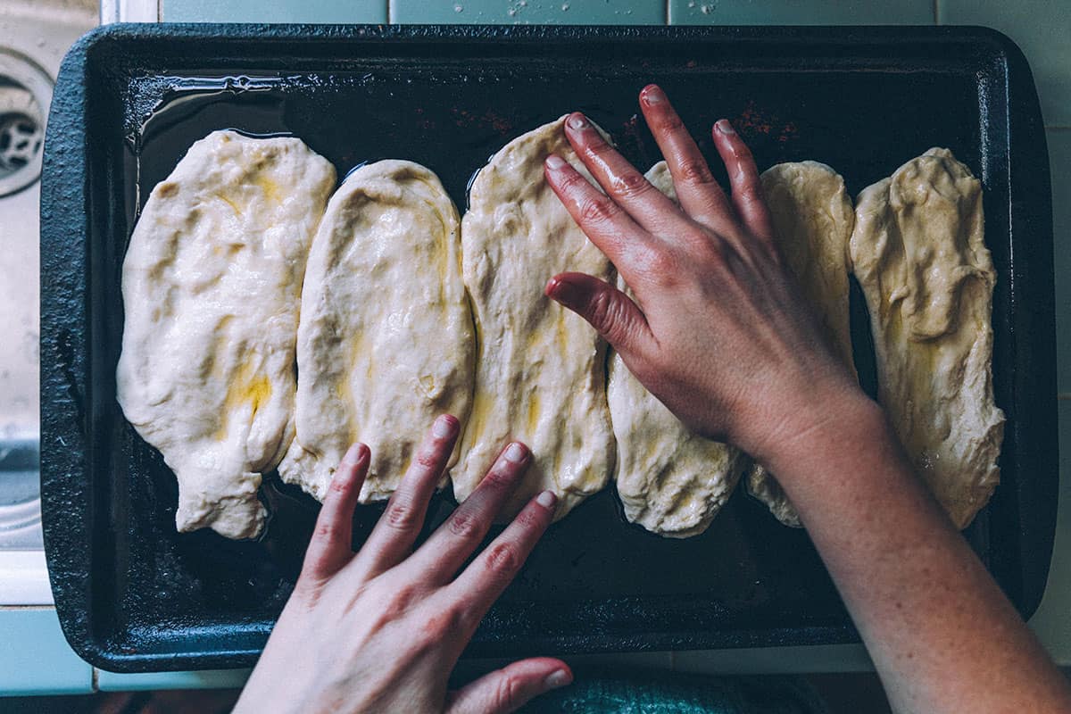 Hands shaping the naan dough. 