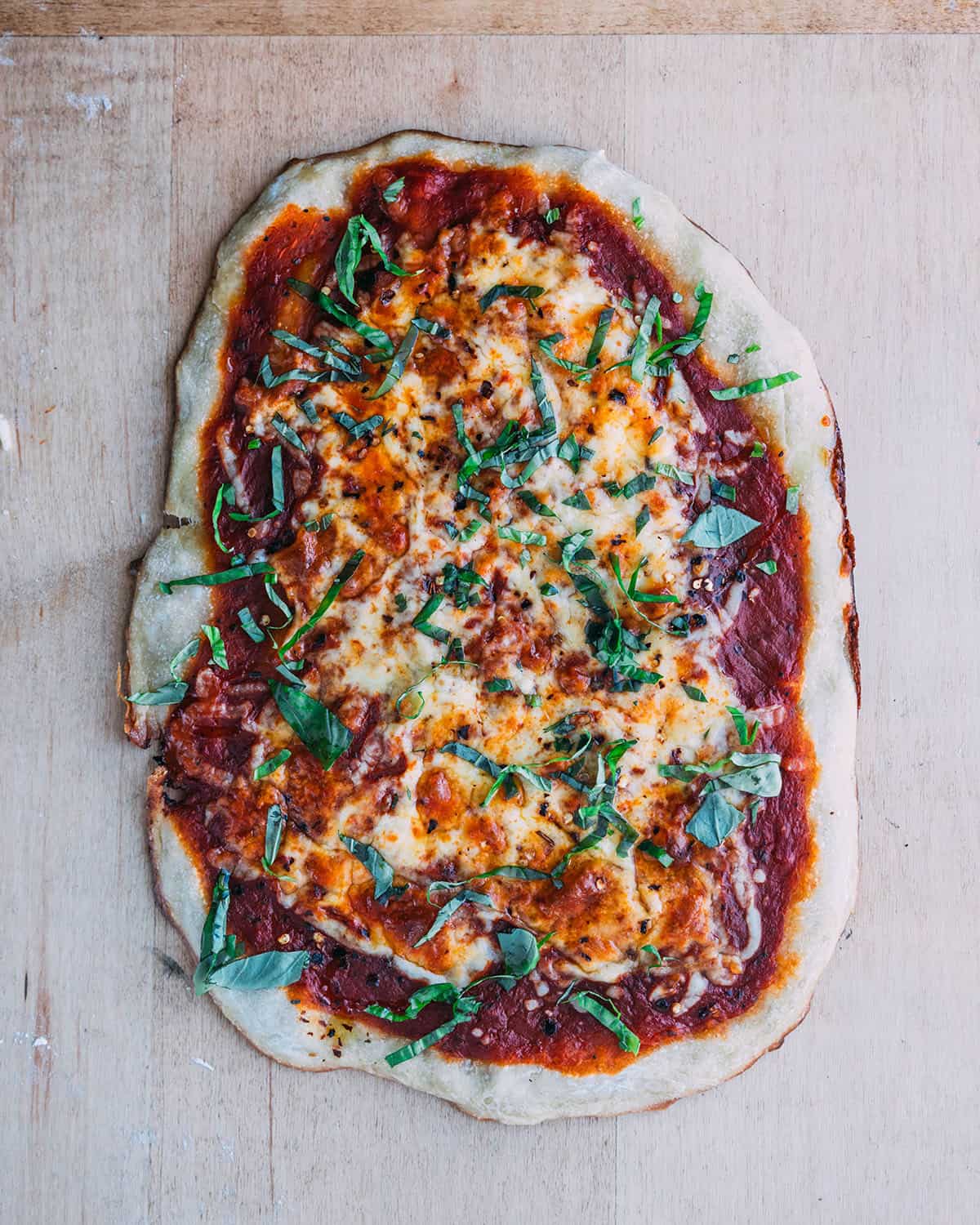 Baked sourdough pizza with red sauce, cheese, and basil. 
