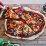 Sourdough pizza cut with a slice being taken out.