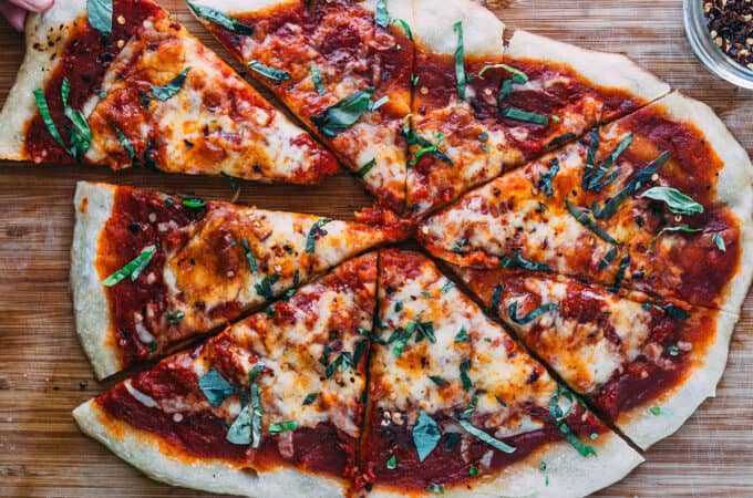 Sourdough pizza cut with a slice being taken out.