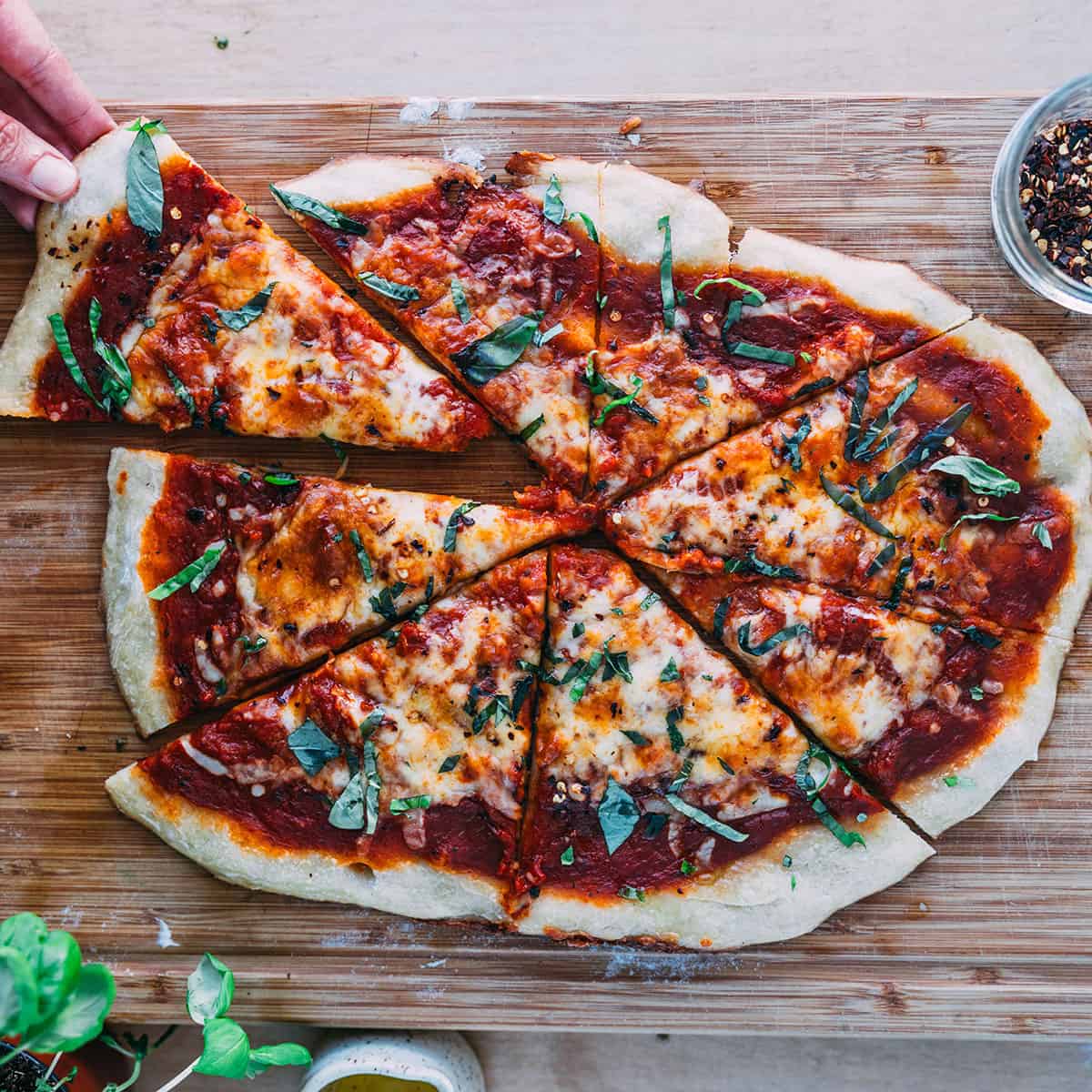 Sourdough pizza cut with a slice being taken out. 