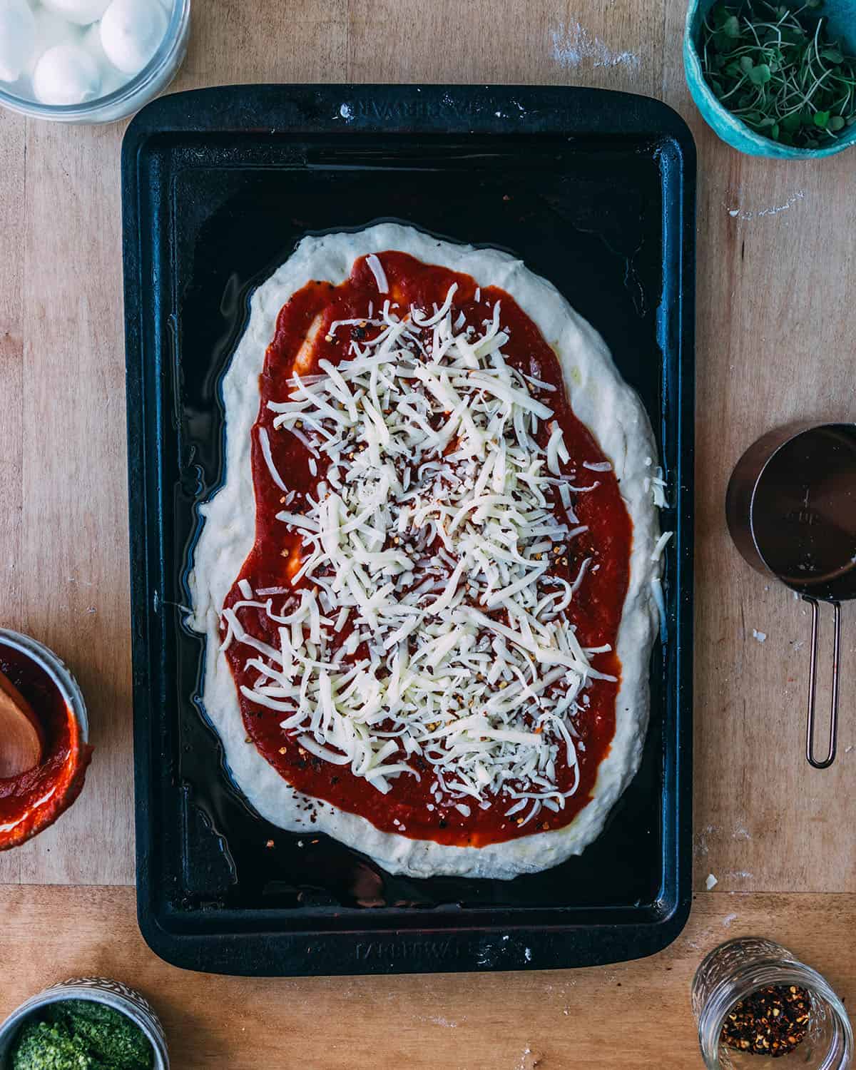 Sourdough pizza dough with red sauce and cheese on it. 