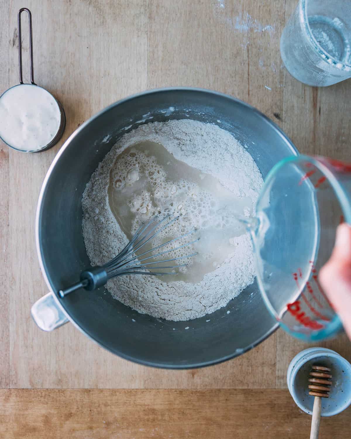 Wet ingredients being added to sourdough pizza dough, top view. 