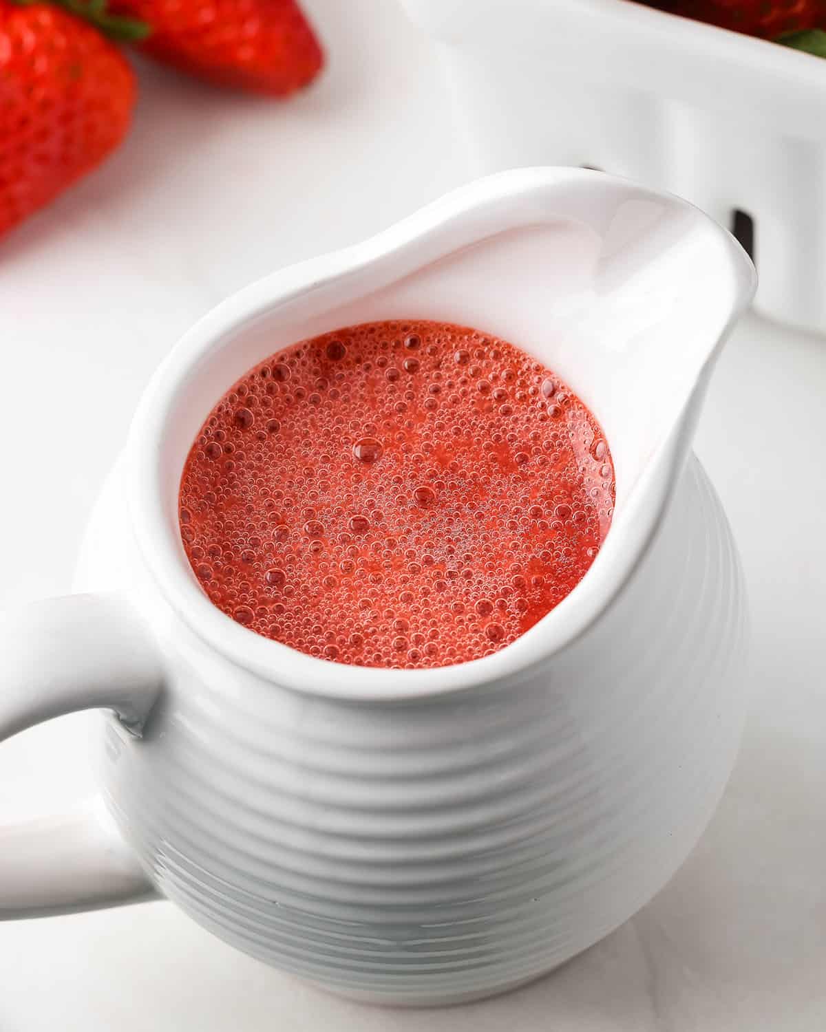 Strawberry puree in a white pouring dish. 