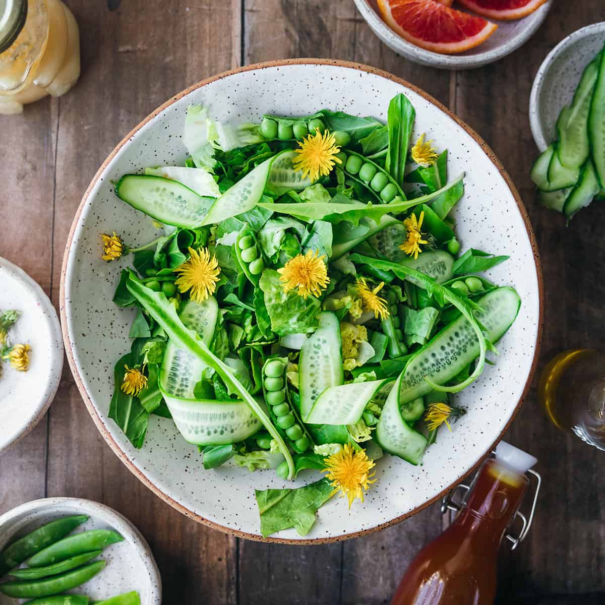 A fresh dandelion salad in a white bowl on a wood surface, top view. 