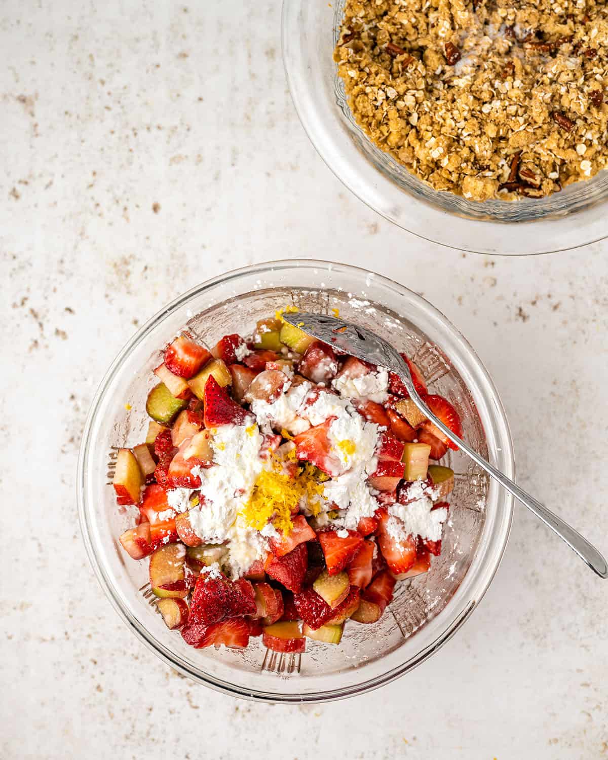 Strawberries and rhubarb with other ingredients being stirred in a bowl, top view. 