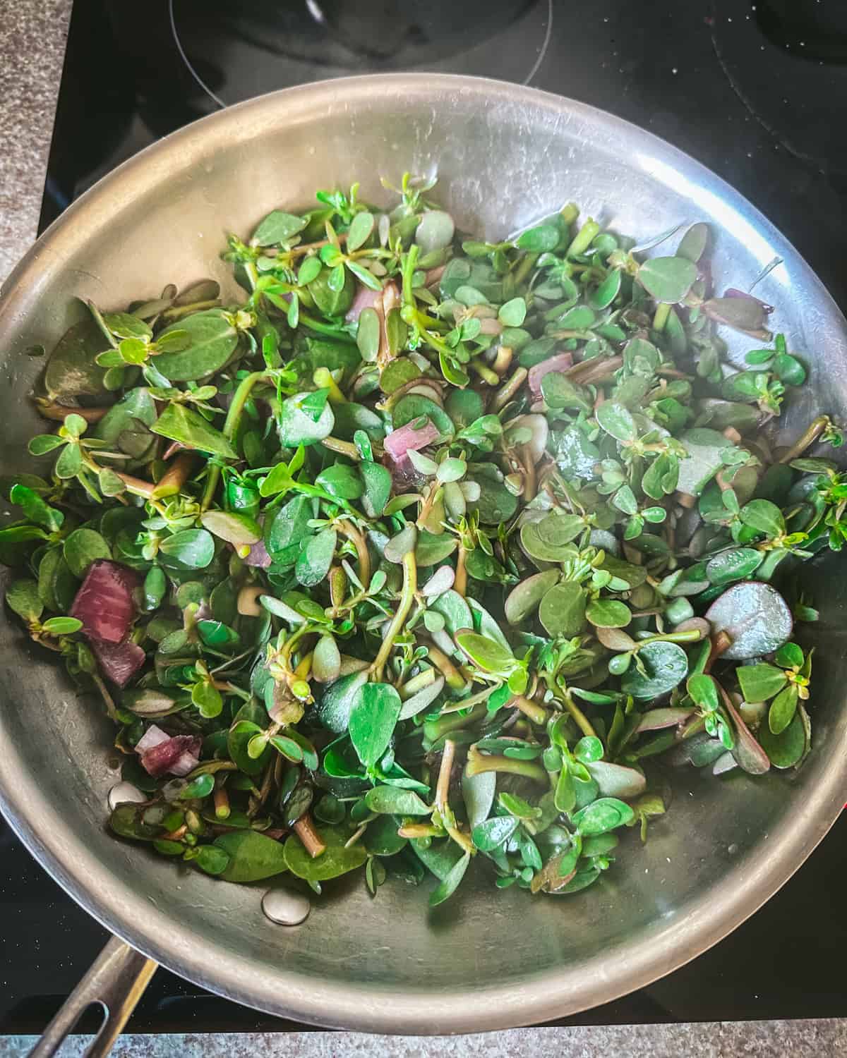 Sautéing purslane in a pan.